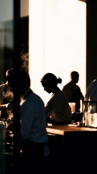 Vertical Silhouetted View of Kitchen Staff Preparing Dinner in Busy Commercial Kitchen at Sunset for Culinary Arts and Fine Dining Concept