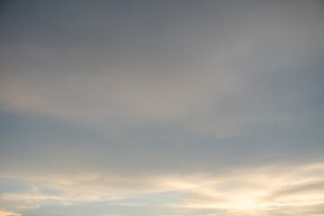Obraz premium Sunset sky with warm golden light breaking through soft grey clouds backdrop