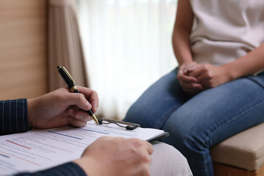 Close-up of psychologist taking notes on clipboard while listening to female patient in therapy session. Concept of mental health counseling, psychotherapy, and medical consultation.
