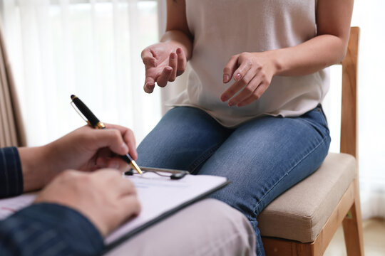 Close-up of psychologist taking notes on clipboard while listening to female patient in therapy session. Concept of mental health counseling, psychotherapy, and medical consultation.