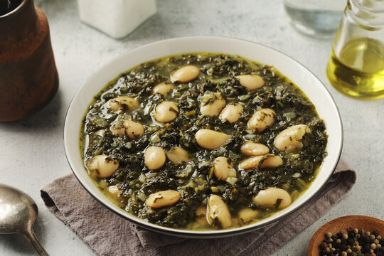 A bowl with traditional Tuscan kale salad and white beans soup Cavolo nero e fagioli