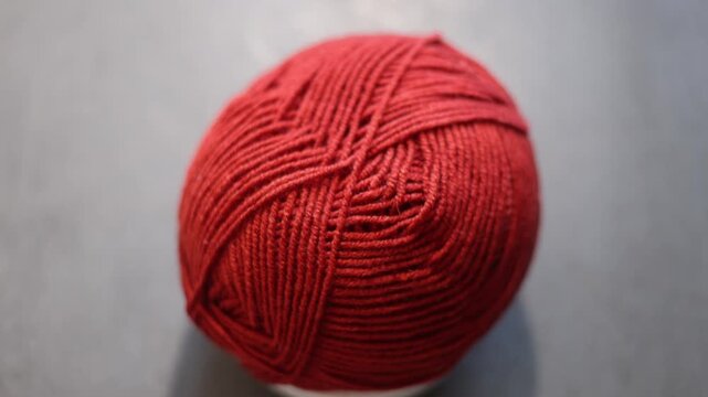 Orange yarn ball with loose thread on a dark background, knitting supply. 
