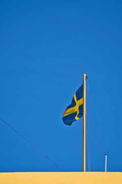 Swedish Flag Waving on Flagpole Against Clear Blue Sky
