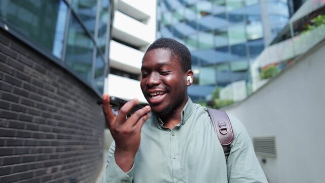 Black businessman sending voice message downtown
