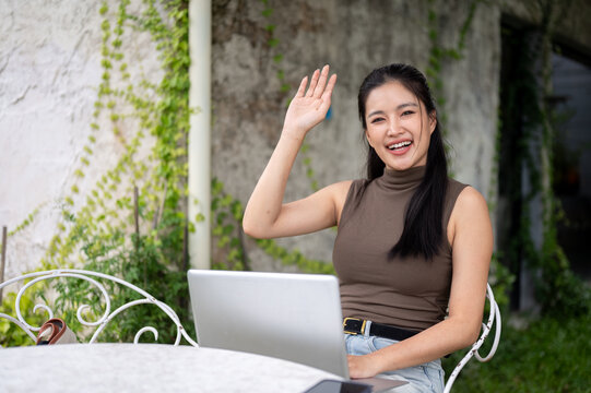 Cheerful Asian Woman Waving Hand In Video Call On Laptop
