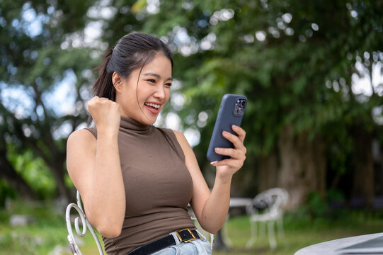 Asian Woman Cheering With Fist Celebrating Success On Phone