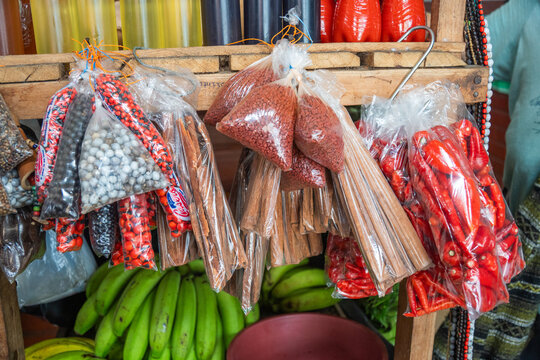 Bottles of oil and chili sauce on a shelf above bags of beads, spices and chilies, at a market in Tena, Ecuador