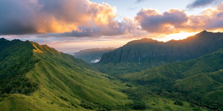 Aerial view of vast rolling green mountain ranges in Hawaii at sunset with dramatic clouds glowing golden and purple overhead rugged cliffs cascading waterfalls visible through lush tropical foliage