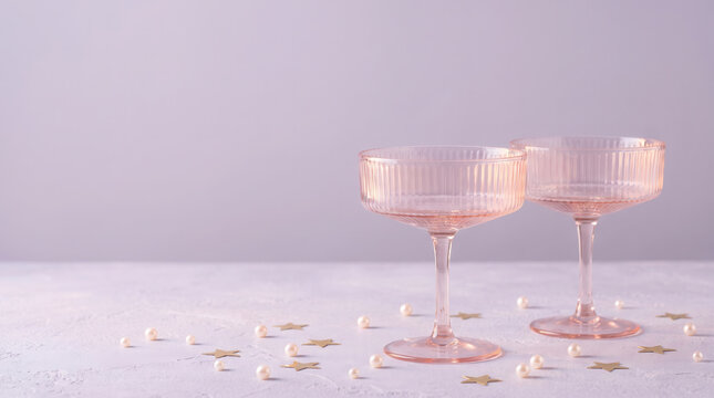 Two pink ribbed champagne coupes styled for Christmas with gold stars and pearls