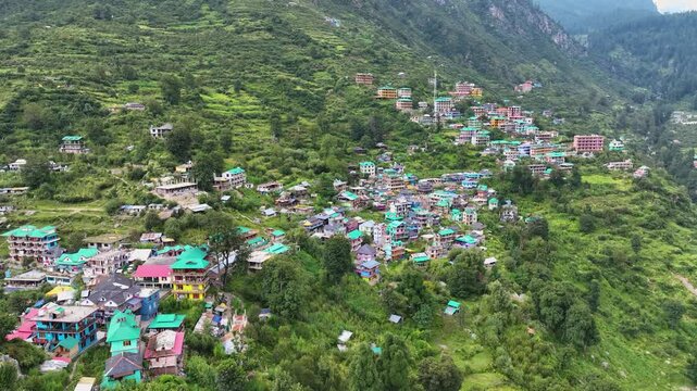 Aerial pullback shot highlighting the extreme topography and isolation of Tosh village, a renowned summer trekking basecamp in Kullu.