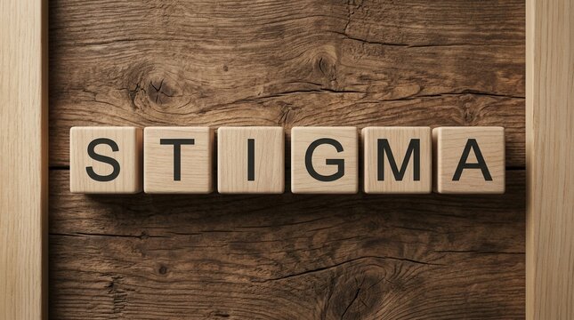 The word stigma spelled out with wooden blocks on a rustic wooden background with shapes.