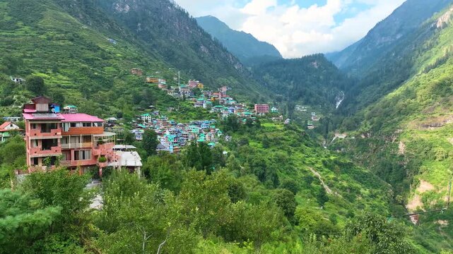 Cinematic drone orbit around the vibrant, multi-level rural architecture of Tosh village, capturing the sweeping scale of Parvati Valley in Himachal Pradesh.