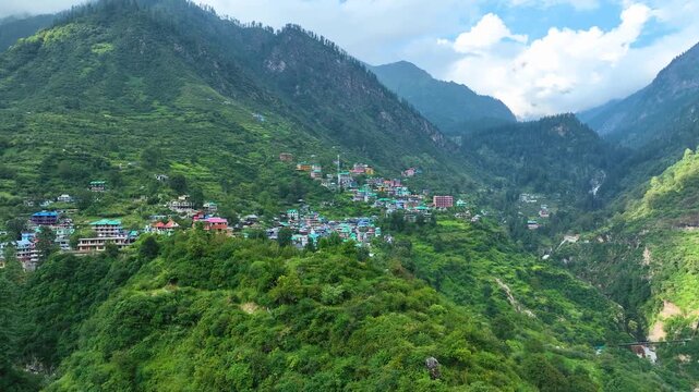 Wide angle drone shot of colorful traditional guest houses in Tosh village perched on a steep Himalayan slope in Kheerganga Valley, India.