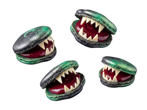Creepy Halloween monster macarons: green and black shells, sharp white teeth, and red jam filling, isolated.