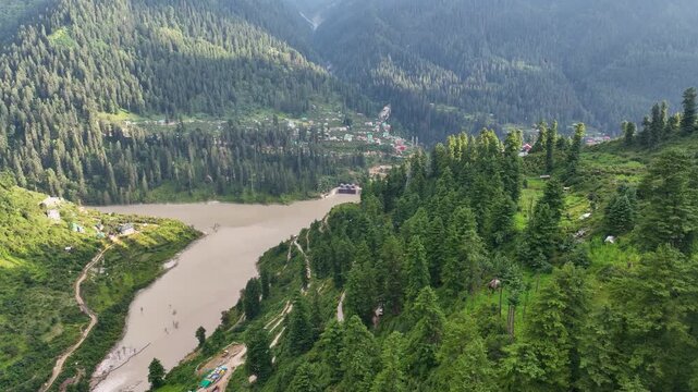 Aerial establishing shot of the Parvati River reservoir and hydroelectric facility near Kasol and Tosh trekking corridors in Himachal Pradesh.