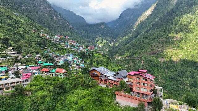 drone shot of colorful traditional guest houses in Tosh village perched on a steep Himalayan slope in Kheerganga Valley, India.