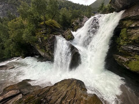 Powerful waterfall cascading through rocky forested gorge in Geiranger, M&oslash;re og Romsdal, Norway, August 2025