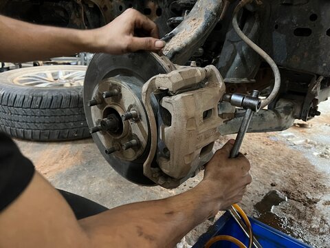 Car suspension and brakes  Mechanical view of suspension coil spring, control arm, and disc brake assembly without wheel.