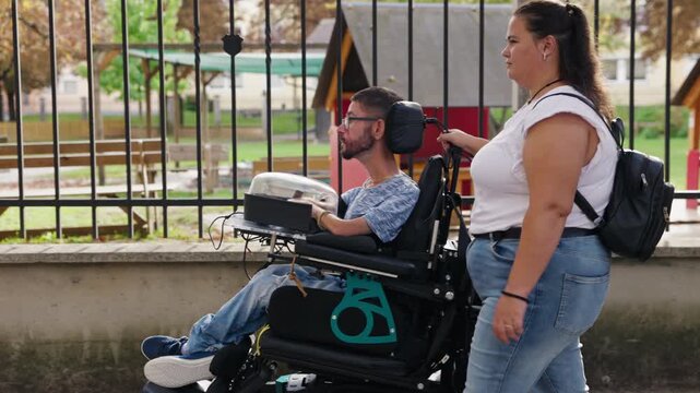 Powered wheelchair user independently navigating a city street, accompanied by a Personal assistant . Independent mobility and inclusion