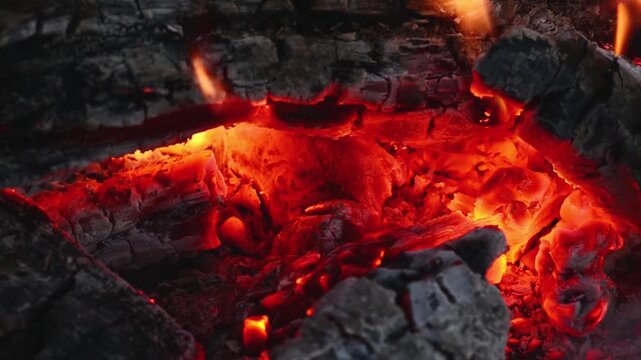 Close up of burning firewood with glowing embers and crackling sound. Macro video of glowing hot embers and burning wood in a campfire with original sound, perfect for ASMR and video backgrounds.