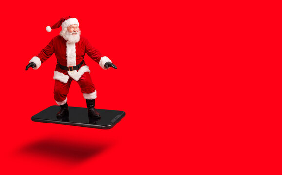 Santa Claus Surfing on a Floating Giant Smartphone Against Red Background