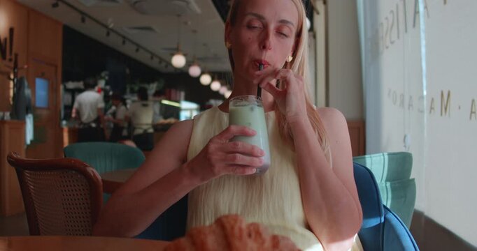 Woman Drinking Matcha Latte with Croissant at Cafe in Tashkent Uzbekistan