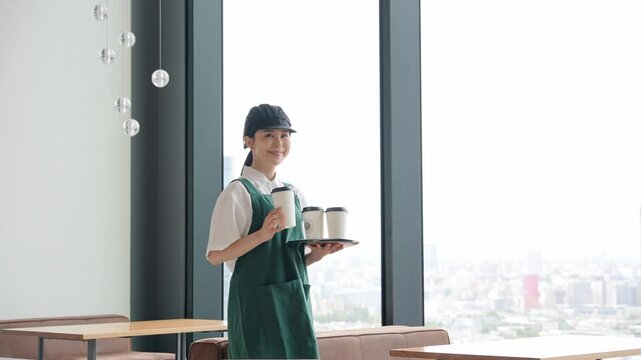 笑顔で紙コップを持つ飲食店店員