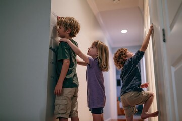 Obraz premium Children playing and measuring height on wall in home hallway