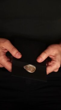 Close-up of a person holding a black envelope sealed with a golden wax seal. Mystery, secret message, letter, and confidentiality concept