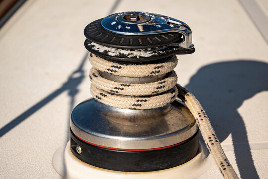Sailboat winch drum wrapped with rope on sunlit deck