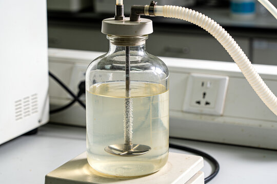 Glass bioreactor vessel with impeller and rising bubbles in lab
