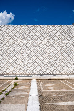 Facade pattern and wall geometry create abstract urban architecture against blue sky with clean exterior symmetry and open space