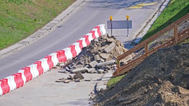 Roadworks Site with Pile of Concrete and Asphalt Rubble on Street Lane Secured with Plastic Safety Barrier