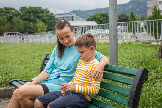 Beautiful mother and her young son relaxing outdoors. Tired child with mom