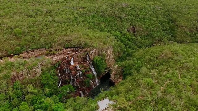 Almecegas II waterfall drops over reddish quartzite ledges into a dark plunge pool surrounded by dense Cerrado scrub near Alto Paraiso de Goias, drone parallax orbit