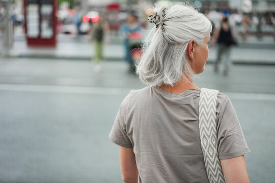 Caucasian senior woman walking at city bus station during evening time - Urban lifestyle concept - UGC content - Main focus on head