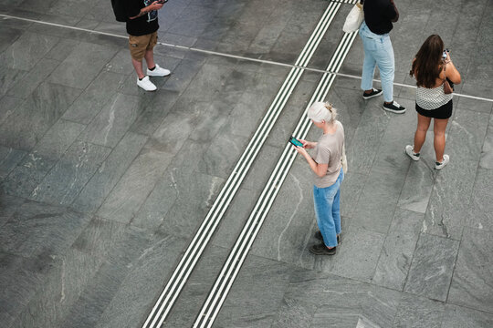 Caucasian senior woman using smartphone at bus station wearing casual clothes - City lifestyle and technology concept - Main focus on body - UGC content