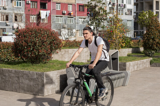 A person rides a bicycle along a pathway in a busy city.