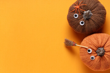 Naklejka premium Halloween celebration and autumn holidays, handmade knitted pumpkins with googly eyes and witch broom on orange background with copy space