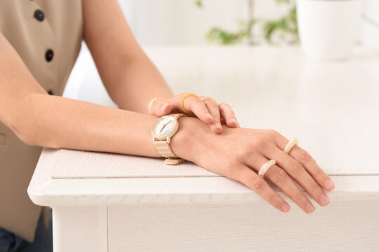 Time management and punctuality concept, woman checking wristwatch for deadline pressure and schedule planning while sitting at a white office desk