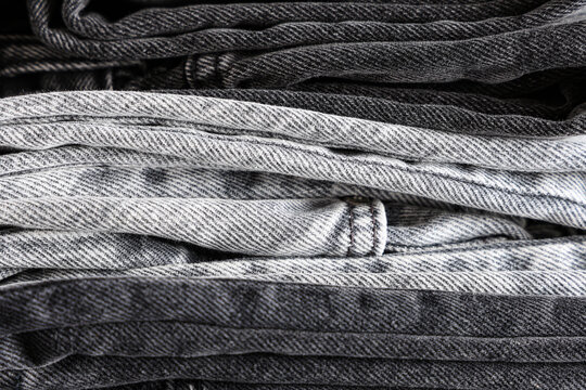 Sustainable fashion and textile industry, stack of folded black and grey denim jeans showing fabric texture and quality craftsmanship in retail store