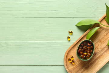Obraz premium Wellness and natural supplements, omega 3 fish oil capsules in bowl with green leaves on wooden tray for healthy lifestyle and holistic medicine