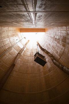 Looking up from the bottom of a deep underground construction shaft with ventilation ducts and muck skip, pipe jacking sewer site