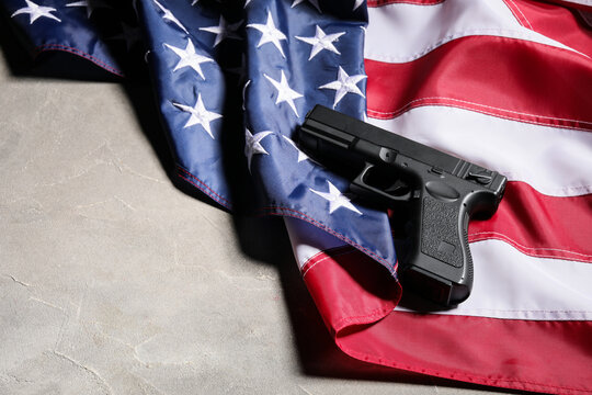 Gun control and second amendment debate, black handgun resting on a folded United States flag on a concrete surface for political news and editorial