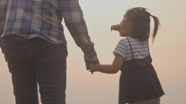 Tender moment between daughter and father, little girl holds and plays her father&rsquo;s hands and pointing out the scenery.