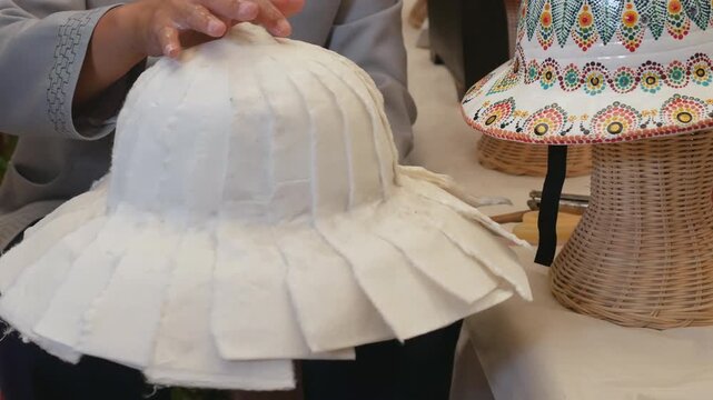 Woman hands making a pith hat or pith helmet from mulberry paper, craftsmanship in the Northern Thailand.