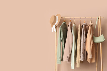 Sustainable fashion and capsule wardrobe, clothes hanging on a wooden rack with a straw hat and...
