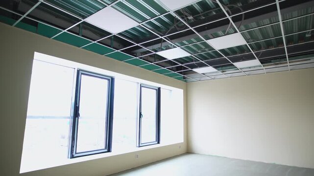 Empty room with glass doors and led lamps on ceiling at construction site. Incomplete business center lobby at commercial real estate