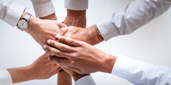 Diverse group of hands joined in teamwork, symbolizing unity and cooperation.