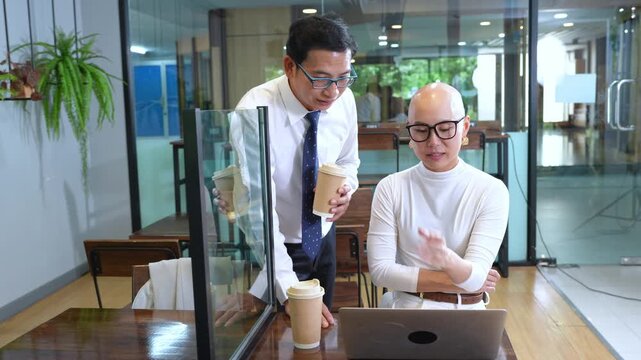 Two business professionals collaborating in a modern coffee shop setting with laptops and refreshments